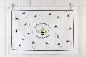 White organic cotton tea towel with bee pattern and custom branding in landscape orientation