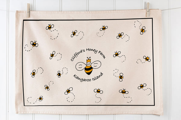 Screen printed landscape tea towel with scattered bee illustration on natural cotton