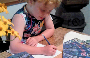 Custom printed tea towel featuring a child’s artwork on white organic cotton, folded neatly on a wooden table