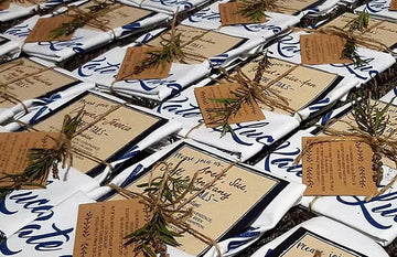 Custom organic cotton tea towel wedding invitations with personalised design, twine wrap, native Australian flora, and kraft card details by Expressions Tea Towels Australia.