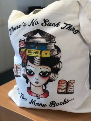 Custom-printed tote bag featuring a vintage tattoo-style illustration of a woman with books stacked on her head, floral accents, and the quote 'There's No Such Thing As Too Many Books' on organic cotton canvas.