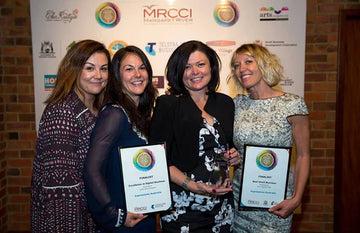 Expressions Tea Towels team celebrating Business of the Year award win, holding trophy at local gala night.