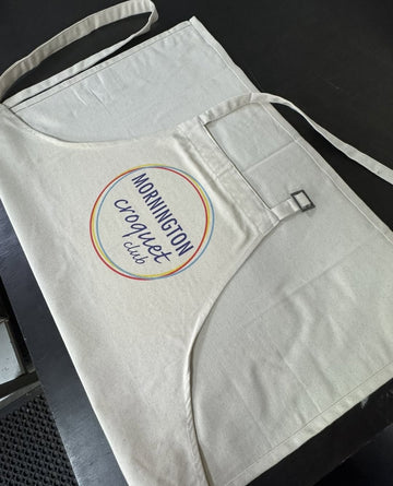 Organic cotton custom apron with Mornington Croquet Club logo printed on the front pocket, featuring an adjustable neck strap.