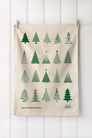 Natural tea towel with Bottle Christmas tree patterns hanging on a white wall.