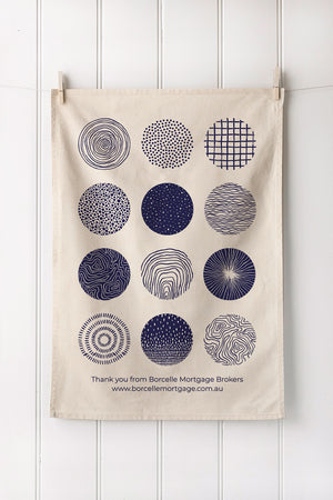 Tea towel with geometric patterns hanging on a white wooden panel