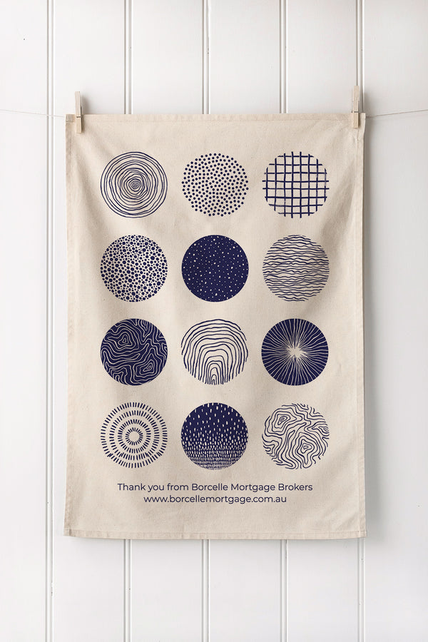 Tea towel with geometric patterns hanging on a white wooden panel