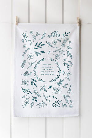 Tea towel with floral wreath design and text on a white background