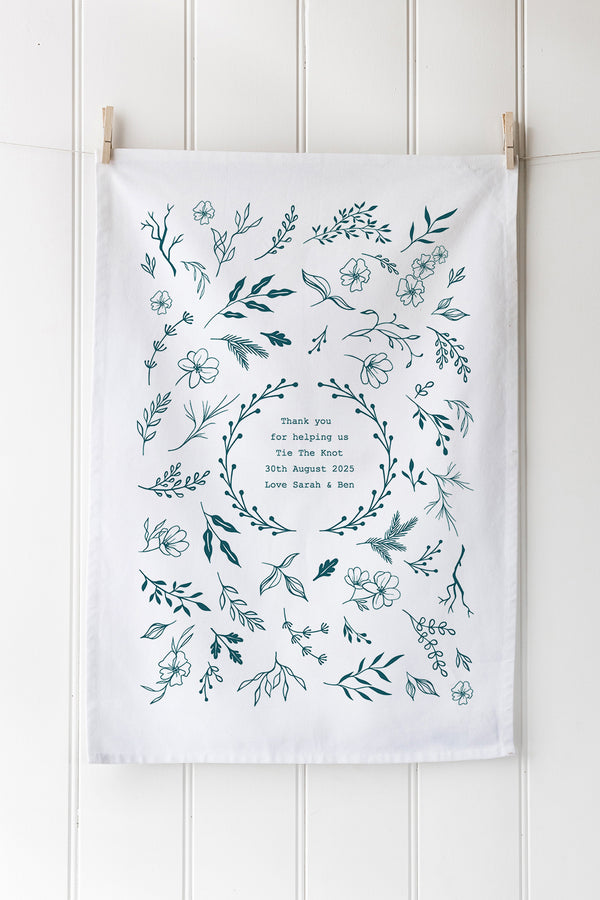 Tea towel with floral wreath design and text on a white background