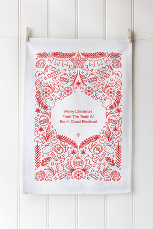 Decorative Christmas-themed tea towel with red designs and custom text on a white background