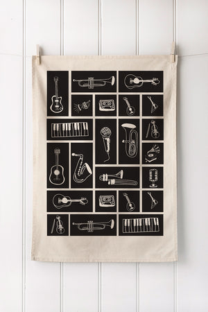 Natural tea towel with musical instrument illustrations on a white wooden background