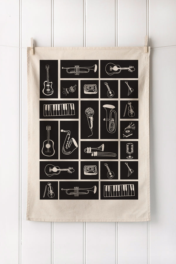 Natural tea towel with musical instrument illustrations on a white wooden background