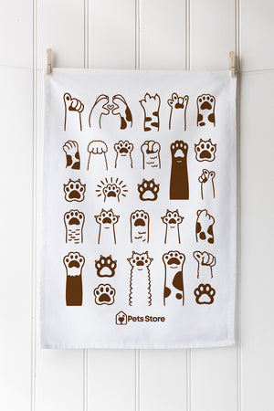White tea towel with brown paw prints and 'Pets Store' logo on a white wooden background