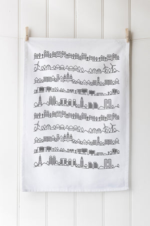 White tea towel with black geometric pattern hanging on a wooden rack.