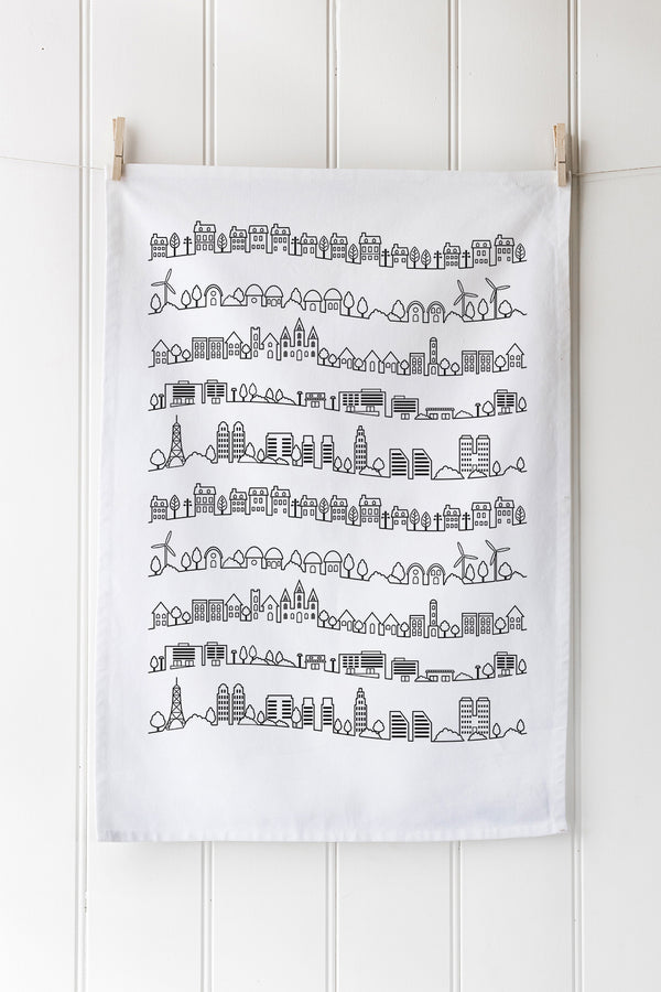 White tea towel with black geometric pattern hanging on a wooden rack.